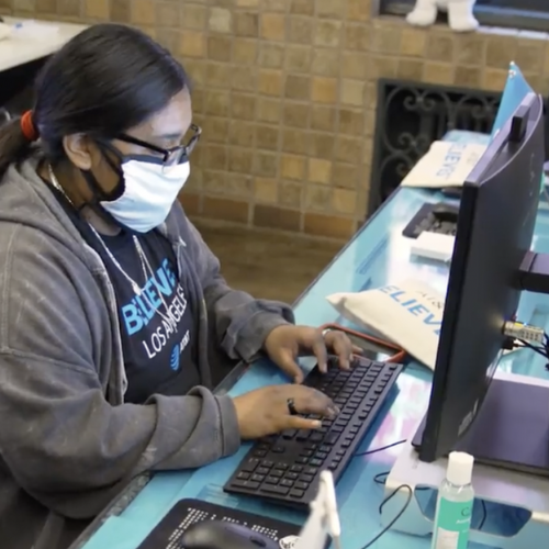 A person wearing a face mask using a public computer workstation at a local career and employment resource center.