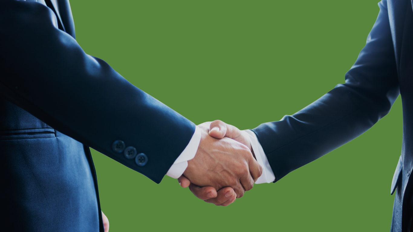 Two individuals in business attire shake hands, conveying professionalism and agreement. Their posture is upright. The background is minimal, keeping the focus on the handshake.